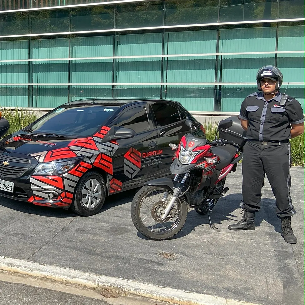 Vigilante Quantum ao lado da moto e da viatura